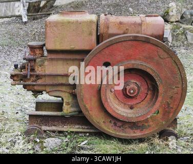 Rusty vintage small tractors diesel engine in forgotten village. The metal equipment is made more than hundred years ago. Mass production Stock Photo