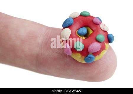 In the future we will eat this concept - mini donut made of clay plasticine on finger. Isolated on white studio macro Stock Photo