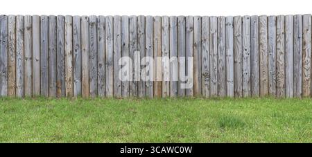 At top of the grassy hill there is a wooden fence from shot vertical pine logs. Isolated on top outdoor summer day image Stock Photo