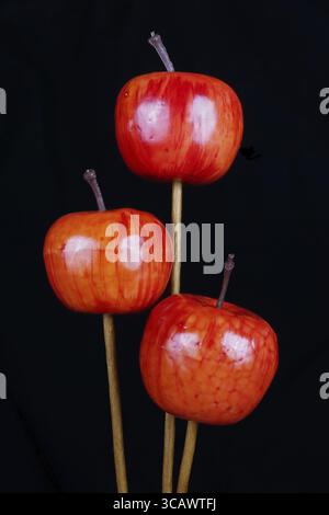 Red handmade artificial plastic apples for fir tree decoration. Night macro on a black background Stock Photo