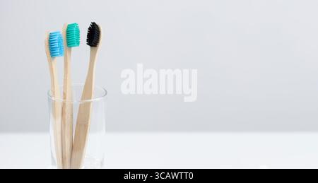 Eco-friendly bamboo toothbrushes neatly placed in a glass holder on a light background, representing sustainable, natural choices for a cleaner, green Stock Photo