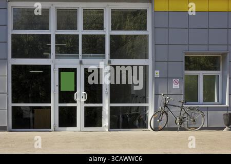 Glass entrance to office. Park zone of the megalopolis. Autumn trees are reflected in windows. Lonely bicycle Stock Photo