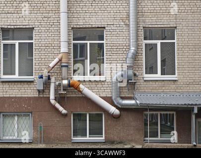 Thick, powerful ventilation pipes air conditioners mounted on the old white bricks school wall Stock Photo