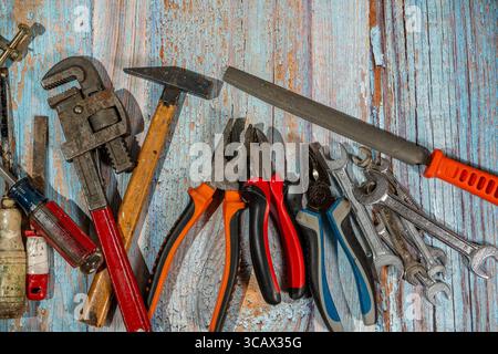 Different work tools such as wrenches, hammer, pliers, screwdriver and rasp lying on old wooden planks Stock Photo