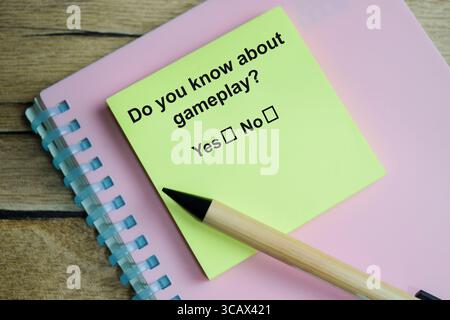 Do you know about gameplay write on sticky notes isolated on Wooden Table. A person is answering question concept Stock Photo