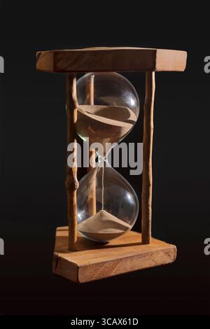 A large hour glass against a black background Stock Photo