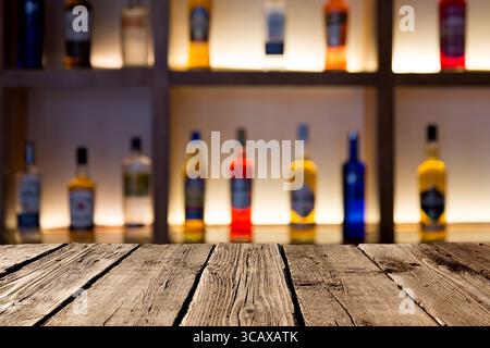 Empty wooden planks against various alcohol bottles in a bar or restaurant. Bar advertisement mockup image. Stock Photo