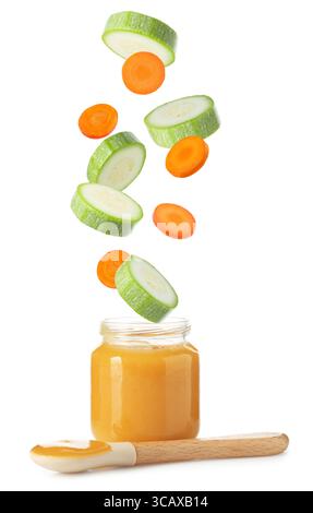 Baby food. Zucchini and carrot slices falling into jar of puree on white background Stock Photo