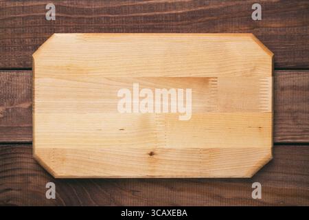 New rectangular wooden cutting board on wooden table background. Top view. Mockup for food project Stock Photo