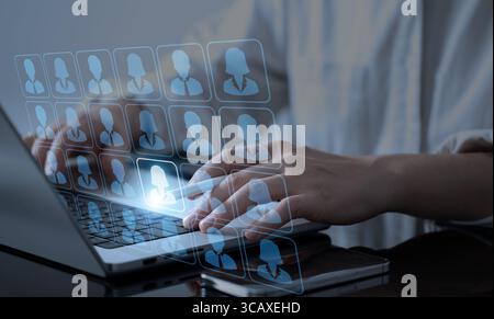 A businessman works on a laptop and interacts with a hologram to choose a key player for his team, supported by AI—highlighting smart hiring and busin Stock Photo