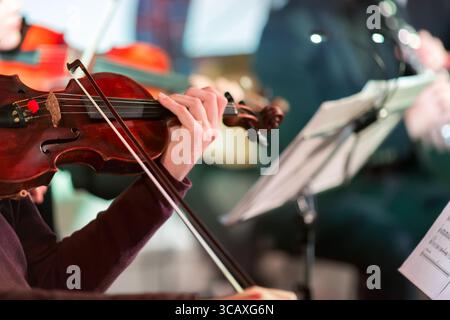 Symphony music. Male musician playing the violin in orchestra. Focus on bow. Stock Photo