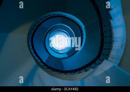 Abstract Blue Spiral Staircase with Circular Light Pattern Viewed from Below in Budapest Architecture Stock Photo