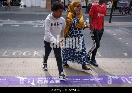 A phone user and other pedestrians walk past pavement messages on Oxford Street that warn them of the increasing trend of phone snatch crime, the 'Mind the Grab' initiative by Westminster, the Met Police and the Currys retailer, on 7th August, 2025, in London, England. Statistics reveal that in 2024, a phone was stolen every 15 minutes in Westminster - 94 a day and over 34,000 in total. Typically, these thefts involve criminals on mopeds or e-bikes snatching phones straight from people’s hands on busy pavements. Stock Photo