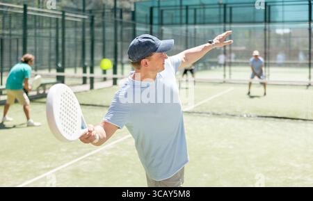 Adult men playing padel against two men Stock Photo