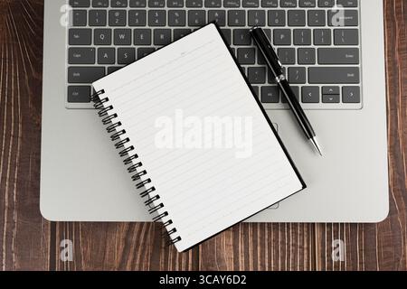 Top view of blank notepad and pen on top of laptop Stock Photo