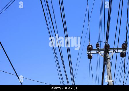 Electric pole with some electric cables on a bright blue sky background. Stock Photo