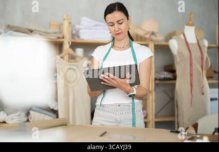 Woman dressmaker makes pattern using tablet Stock Photo