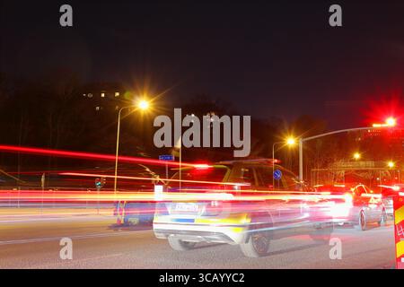 Speed light at night from cars. One Swedish police car at a red traffic light. Long exposure photo. Stock Photo