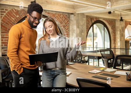 Multiethnic team members collaborating and smiling while working on business project Stock Photo