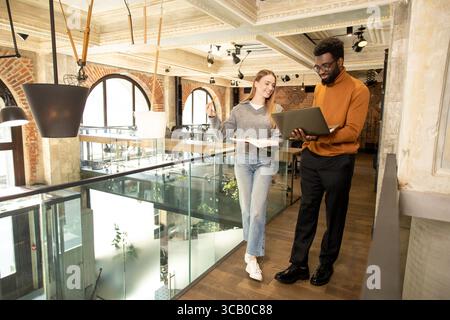 Multiethnic team members collaborating and smiling while working on business project Stock Photo