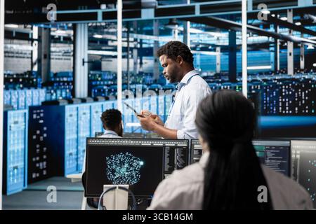 Data center system administrator deploys AI visualization tool to forecast infrastructure demands and optimize resource allocation. Server hub IT expert uses artificial intelligence for maintenance Stock Photo