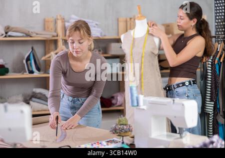 Women tailors design clothes and draw on paper in the workshop Stock Photo