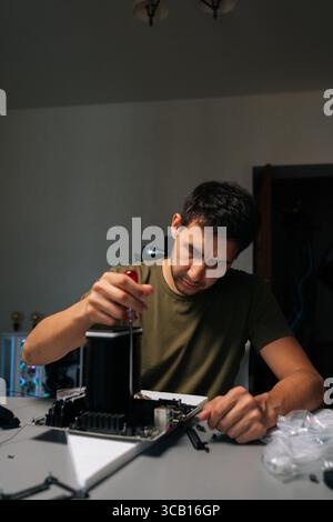 Vertical portrait of computer technician carefully installing CPU cooler onto motherboard, performing essential maintenance and upgrades on desktop Stock Photo