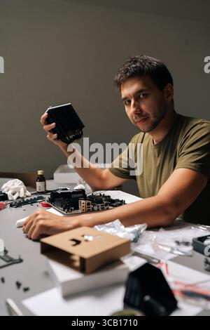 Skilled technician mounting CPU cooler on motherboard, performing precise hardware maintenance inside specialized computer repair workspace Stock Photo