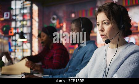 Customer support workers assisting clients to meet outbound call quotas and sales targets. Call center agents contacting prospects to inform them about new products, camera B Stock Photo