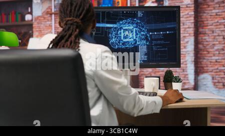 Freelancing computer engineer doing maintenance on artificial intelligence systems. Remote tech support specialist at working from home, doing checkup on AI systems, happy with results, camera B Stock Photo