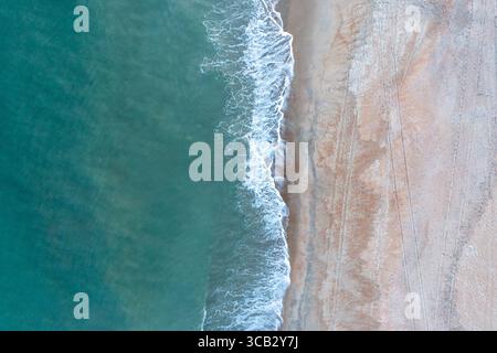 Aerial view top down of calm ocean waters on the shore of an empty beach Stock Photo
