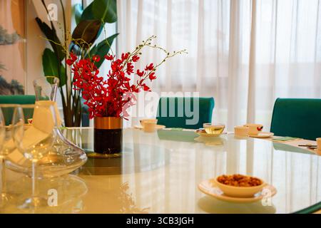 elegant restaurant table setting with red orchids centrepiece, teal chairs and tea cups ready for service Stock Photo