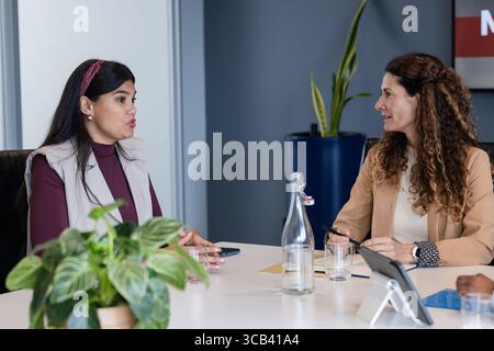 Diverse coworkers discussing paper documents and reviewing data on tablet in meeting room Stock Photo
