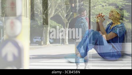 Fusing man pausing at street crosswalk with woman in scrubs meditating in park, with traffic light Stock Photo