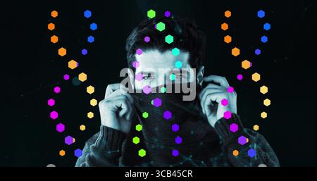 Pulling sweater collar, adult male covering lower face in tech studio, with neon hexagons Stock Photo