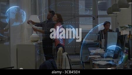 Reviewing printed document, two colleagues collaborating in tech office with holographic globes Stock Photo