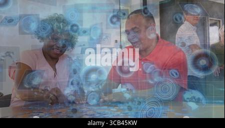 Arranging family members placing jigsaw puzzle pieces on wooden kitchen table, with digital overlay Stock Photo