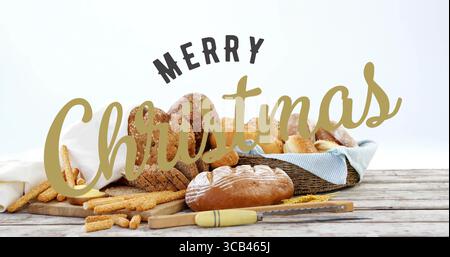 Bread assortment sitting on tabletop, with wicker basket, serrated knife, Merry Christmas lettering Stock Photo