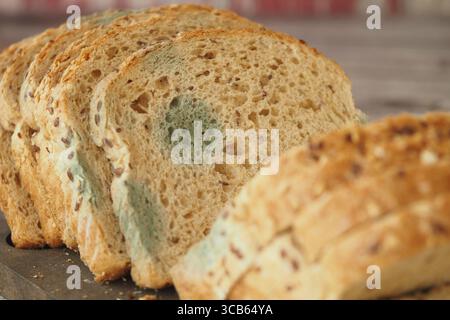 Moldy bread slices on a wooden surface ready for disposal Stock Photo