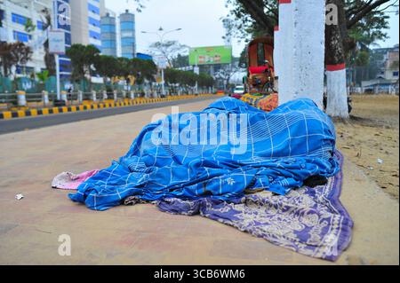 January 5, 2024: Sylhet-Bangladesh: Floating people sleep in the foggy winter  morning on the sidewalk next to the Sylhet Alia Madrasah grounds. Due to the increase in the prices of daily necessities, people are moving from poverty to more poverty, they are moving from villages to cities in search of work. The photo was taken early Friday morning. ....According to the population census in 2011 by the Bangladesh Bureau of Statistics (BBS), the Sylhet population was 479,837. The present population growth rate in Sylhet town is 2.5% per year. Considering 10% floating population comes to the city Stock Photo