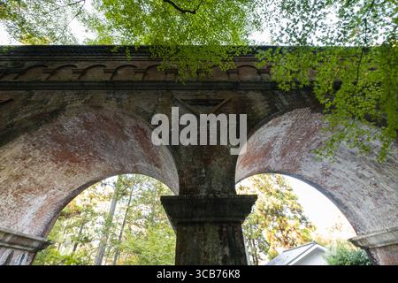 historic brick Nanzen-ji Suirokaku aqueduct  built in the Meiji Period  with soaring arches framed by lush green trees, Kyoto, Japan Stock Photo