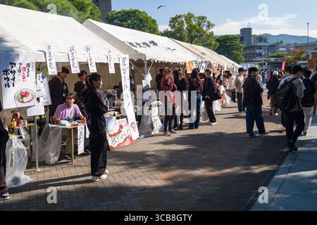 Kyoto University fall festival showcasing food stalls, people walking, enjoying food, and a lively atmosphere. Stock Photo