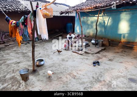 Father and son cooking breakfast in an outdoor kitchen in a yard of a traditional house made from mud in a remote part of India Stock Photo