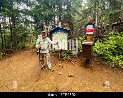 A hiker stands beside a trailhead map, Timberline trail, Mount Hood, Mount Hood National Forest, Clackamas County, Oregon, USA Stock Photo