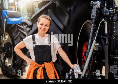Young woman machinery operator posing near tractor Stock Photo