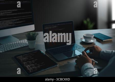 Modern workspace of a UX UI designer and developer working with code editors on a MacBook, iPad, and desktop computer. Creative tech desk setup for we Stock Photo
