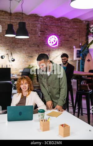 Multi ethnic team collaborating on laptop in modern office Stock Photo