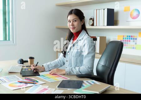 Focused designer. Young woman sketching ideas while seated at her desk. Stock Photo