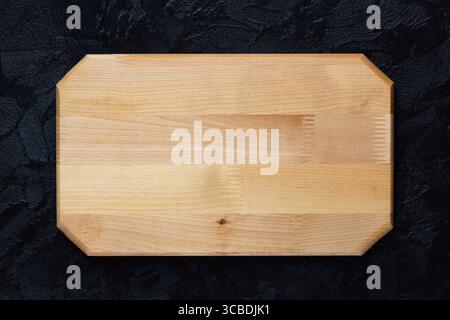 New rectangular wooden cutting board on on black stone slate plate. Mockup for food project. Top view. Stock Photo