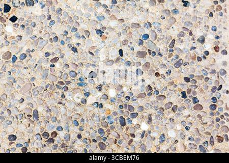 Stones of various shapes and colors are laid out on the road as a sidewalk close-up. Stock Photo